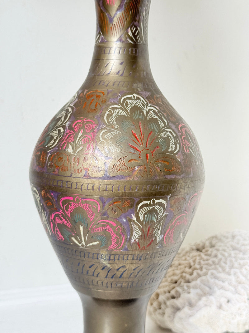 Vintage Indian engraved brass vase with enamel floral decoration and aged patina styled with dried stems on white surface