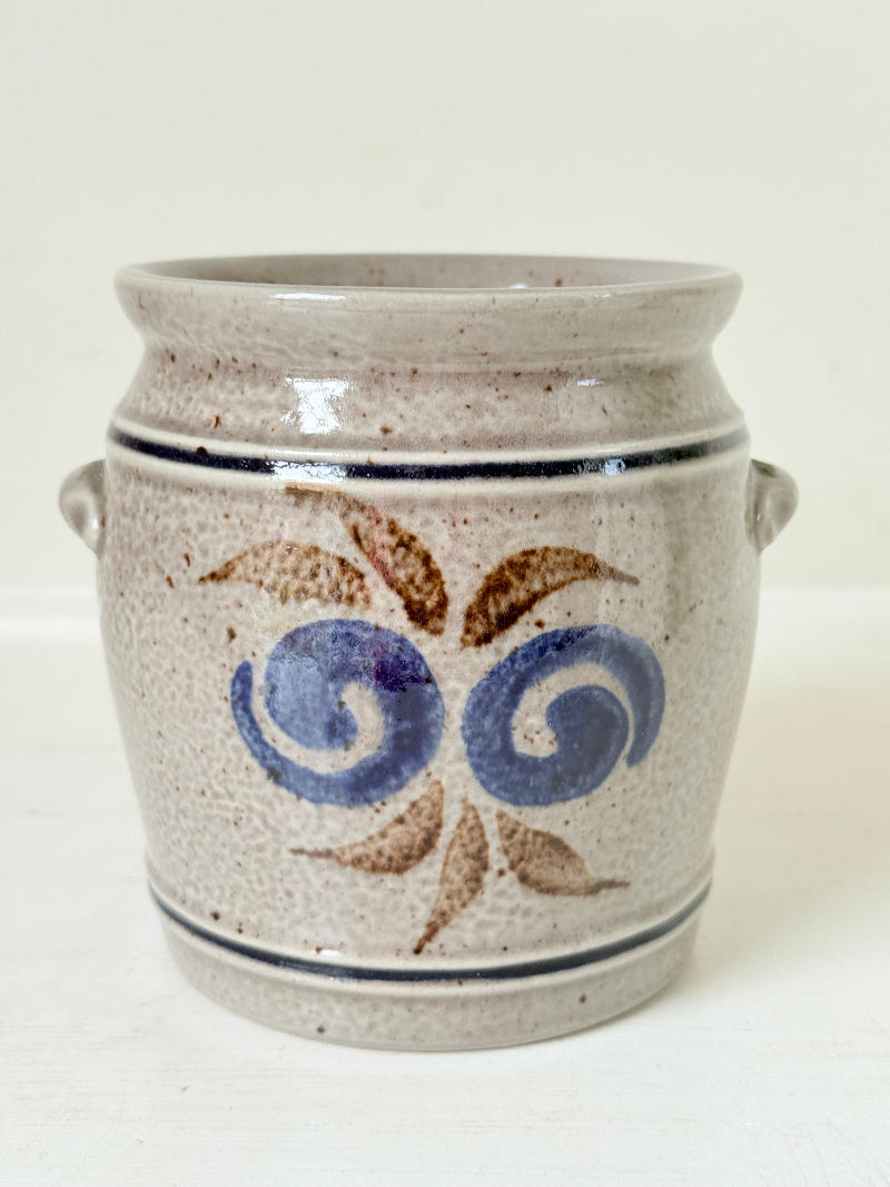 Vintage stoneware confit pot with blue and brown folk art design, photographed on a white surface