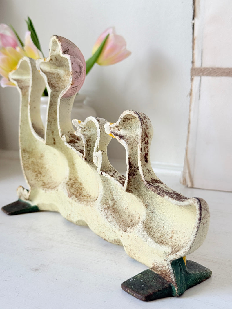 A vintage-style cast iron duck figurine set featuring a large mother duck with three smaller ducklings, finished in a distressed cream and brown glaze with dark green feet, displayed on a white surface.
