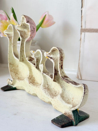 A vintage-style cast iron duck figurine set featuring a large mother duck with three smaller ducklings, finished in a distressed cream and brown glaze with dark green feet, displayed on a white surface.