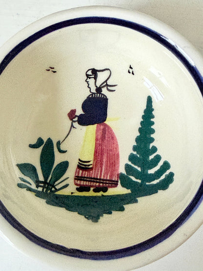 French Quimper faience handled olive bowl with Petit Breton figure and blue rim, photographed on a white surface