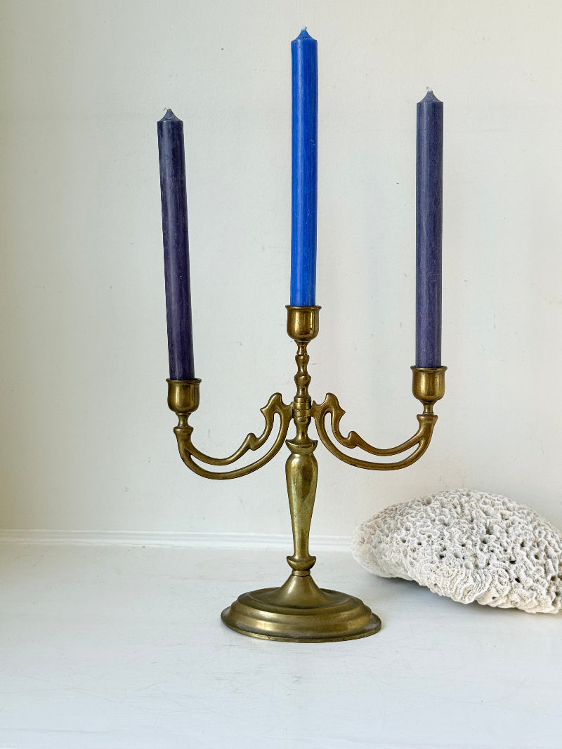 Vintage brass three-arm candelabra with curved arms and soft patina, photographed on a white surface