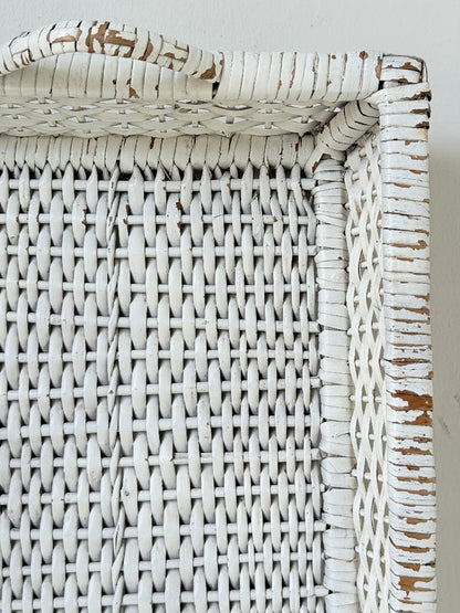 Vintage white painted wicker tray with woven handles photographed on a white surface