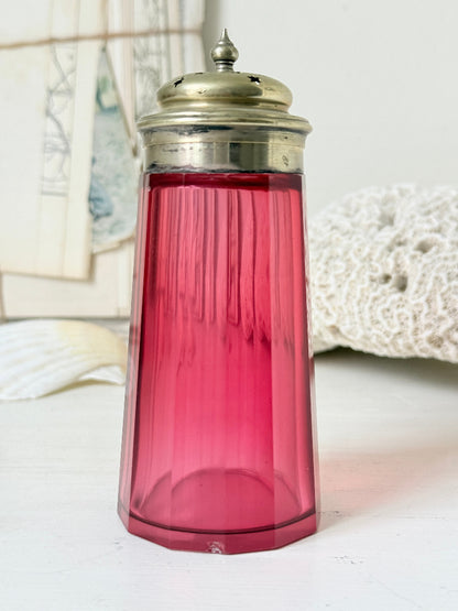 Antique cranberry glass sugar shaker with ribbed optic body, pierced metal top, star holes and deep pink glass