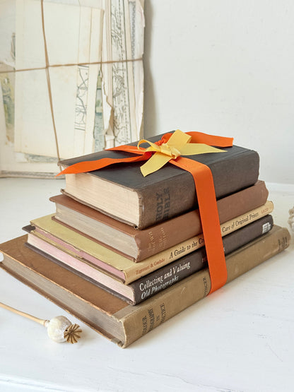 Vintage decorative book bundle in orange and brown with aged hardback covers and bright orange ribbon for shelf styling