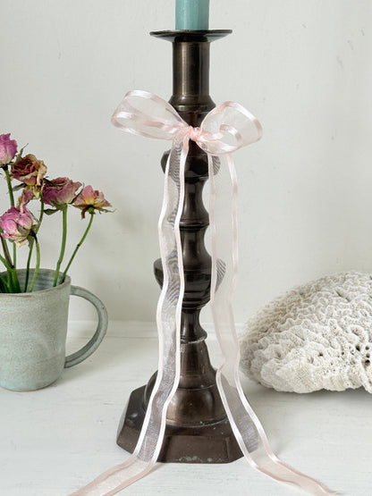 Bronze coloured vintage candlestick with bobbin stem and shaped base styled with taper candle on white surface