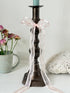 Bronze coloured vintage candlestick with bobbin stem and shaped base styled with taper candle on white surface