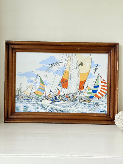 Vintage enamel artwork of sailing yachts with colourful striped sails in a regatta, framed in wood, photographed on white surface.