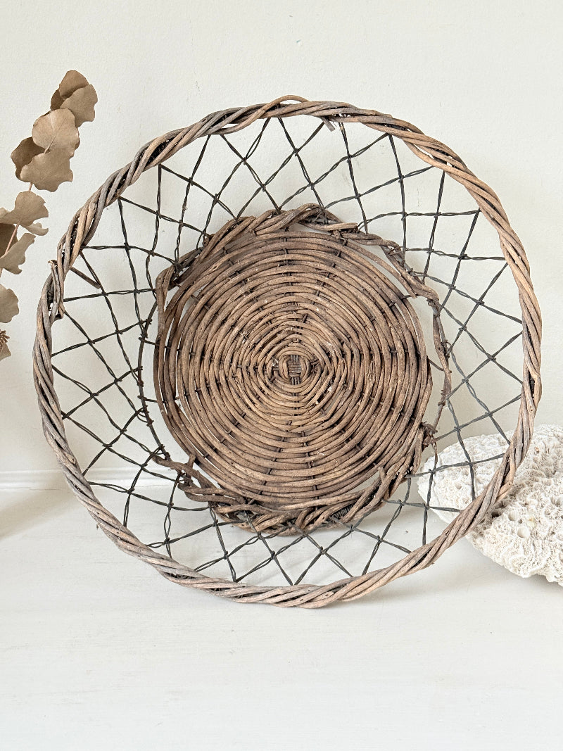 Vintage wicker and wire basket with woven base photographed on a white surface