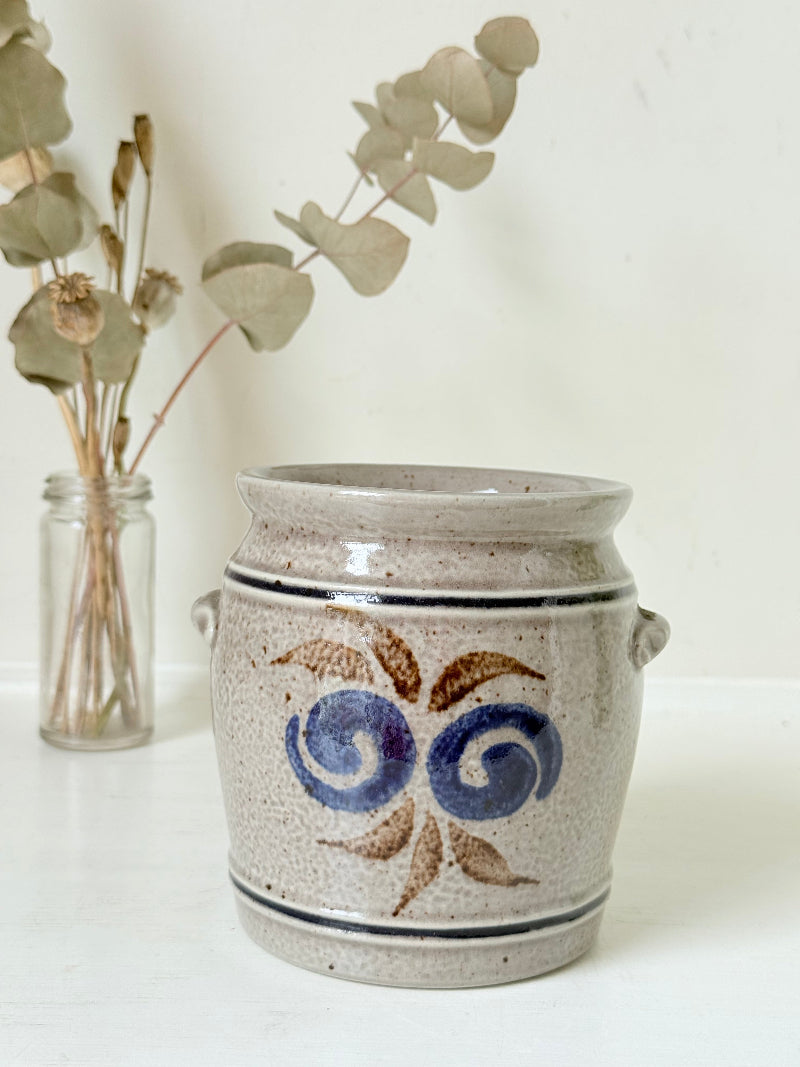 Vintage stoneware confit pot with blue and brown folk art design, photographed on a white surface