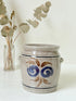 Vintage stoneware confit pot with blue and brown folk art design, photographed on a white surface