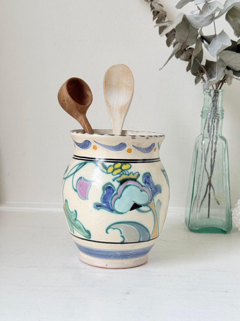 Hand painted floral pottery vase in blue and green on cream, photographed on a white surface