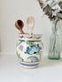 Hand painted floral pottery vase in blue and green on cream, photographed on a white surface