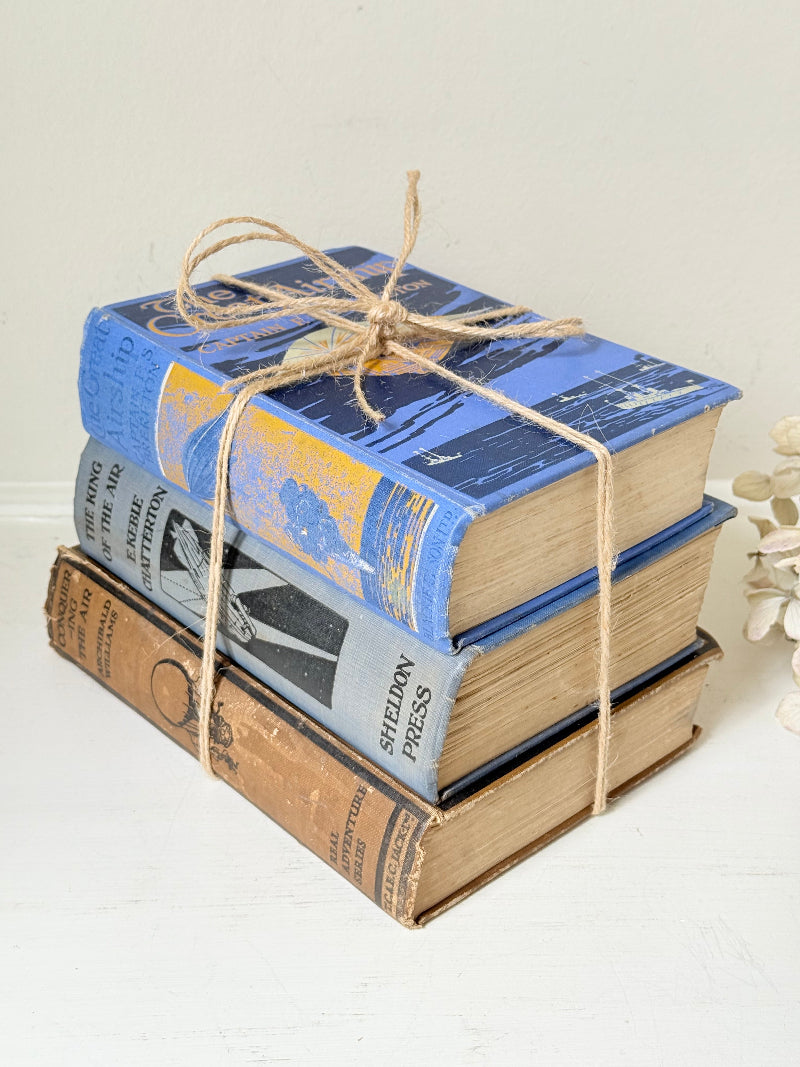 Vintage book bundle in blue, brown, and cream with printed lettering, tied with twine, photographed on a white surface