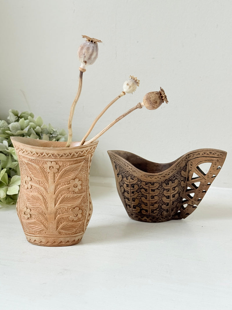 Pair of hand carved wooden jug and vase in contrasting light and dark tones, styled with dried poppy heads on a white surface.