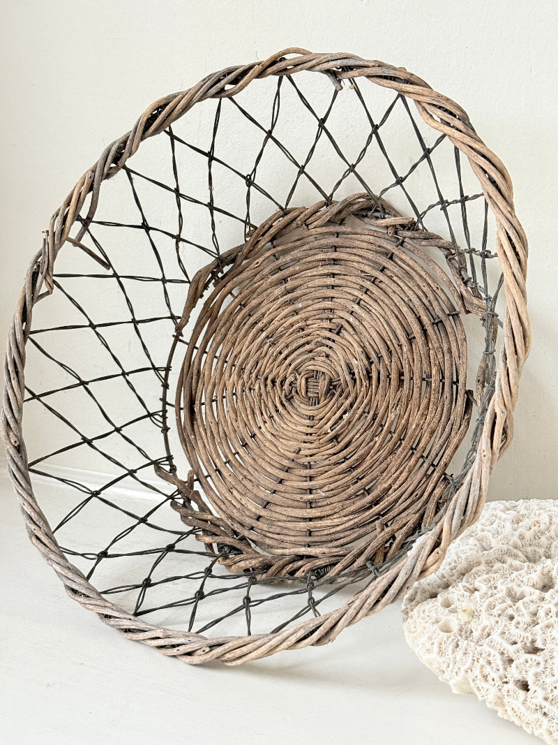 Vintage wicker and wire basket with woven base photographed on a white surface