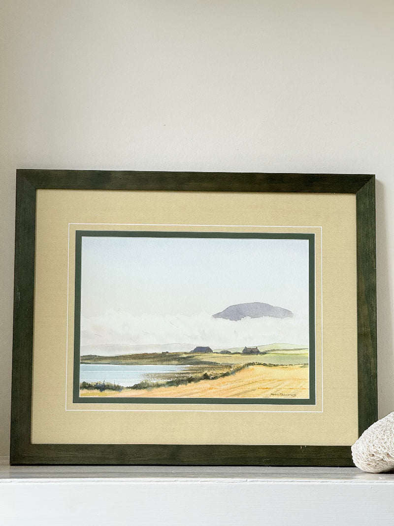 Framed Scottish watercolour coastal landscape by Martin W. M. Prentice in green frame with double mount, on white surface.