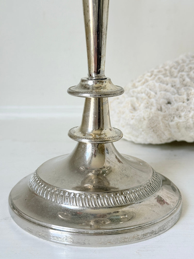 Vintage silver plated three arm candelabra with gadrooned detail and blue green taper candles styled on a white surface