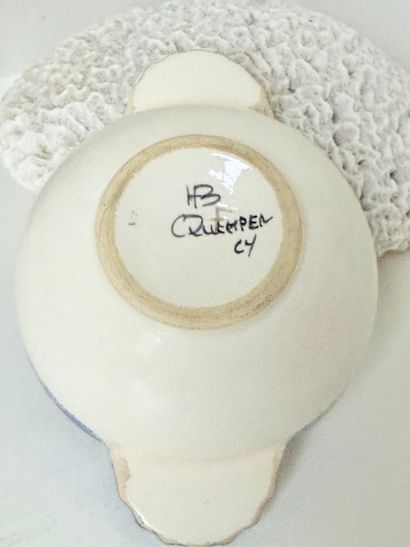 Quimper faience olive bowl with Petit Breton figure and blue speckled rim photographed on a white surface