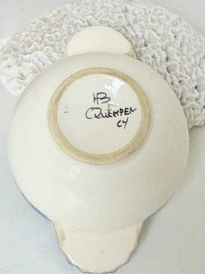 Quimper faience olive bowl with Petit Breton figure and blue speckled rim photographed on a white surface