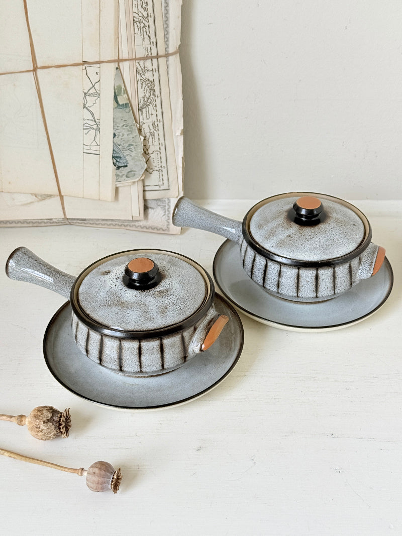 Denby Studio pair of lidded soup bowls with stands in grey and rust photographed on a white surface