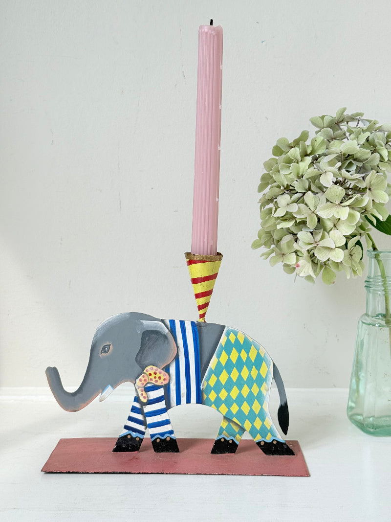 Hand painted metal elephant candlestick in circus-style decoration with colourful patterns, photographed on a white surface