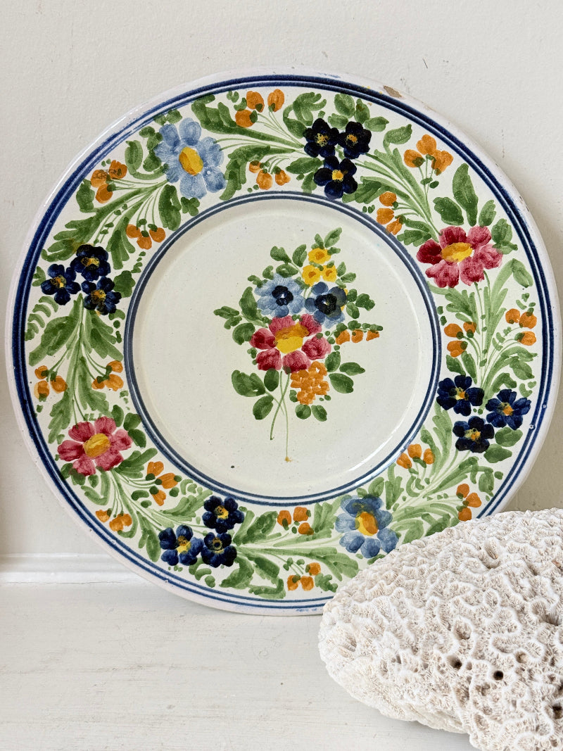 Vintage Italian majolica floral plate with blue green yellow and pink decoration photographed on a white surface
