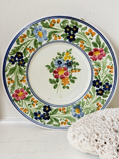 Vintage Italian majolica floral plate with blue green yellow and pink decoration photographed on a white surface