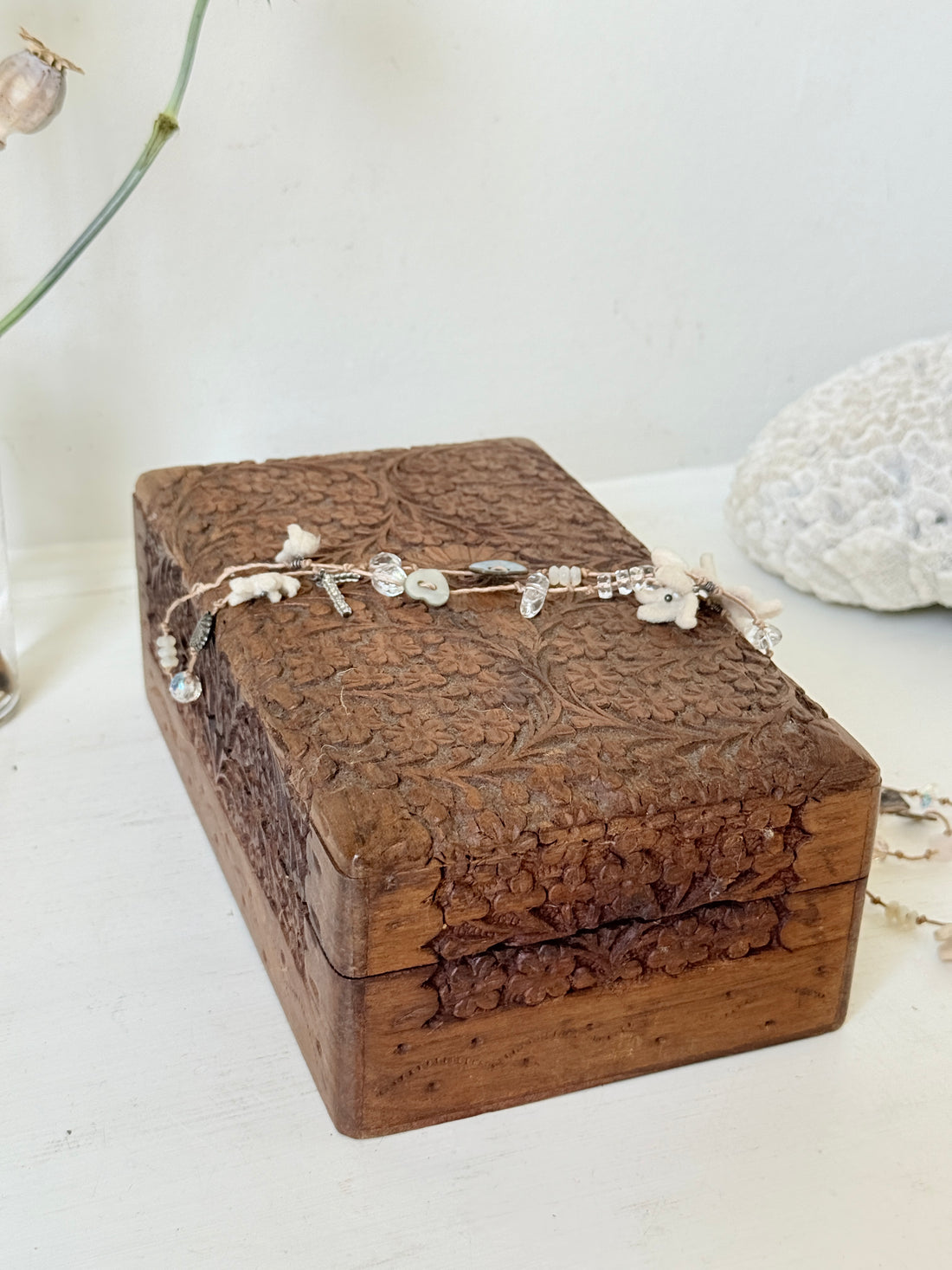Vintage floral carved wooden jewellery box with detailed hand carved decoration, photographed on a white surface