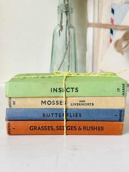 A stack of four hardcover books tied with yellow-and-white string, featuring titles &