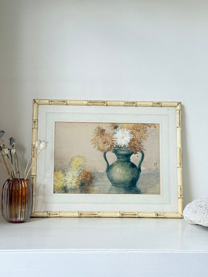 Vintage watercolour of chrysanthemums in green vase, under glass, in cream faux bamboo frame, photographed on white surface.