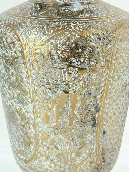 Indian Benares brass lidded vase with engraved figures and pedestal base, photographed on a white surface