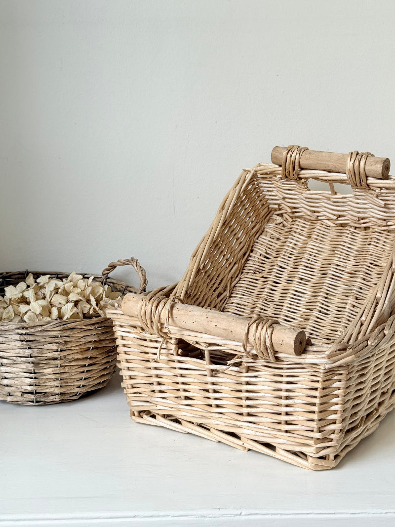Set of three vintage woven willow baskets in natural tones photographed on a white surface