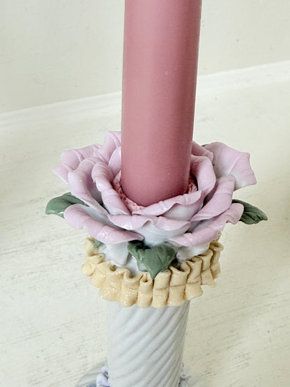 Pair of vintage floral ceramic candlesticks with rose candle cups and pink taper candles styled on a white surface