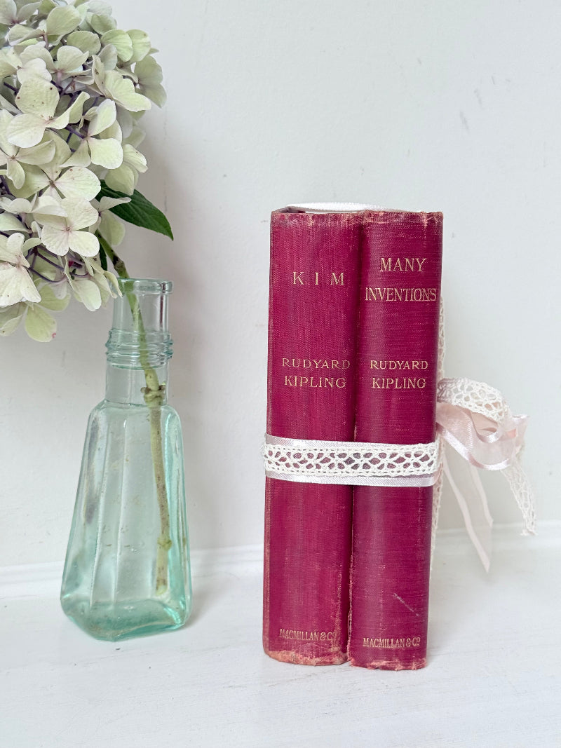 Pair of vintage Rudyard Kipling books in red cloth bindings with gilt lettering, styled as a decorative bundle, photographed on a white surface