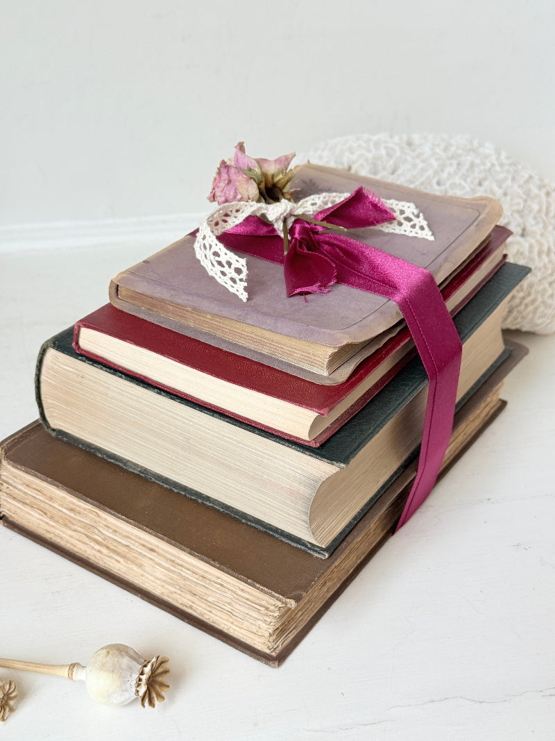 Vintage decorative book bundle with pink ribbon, dried flower detail and aged hardback covers for shelf and table styling