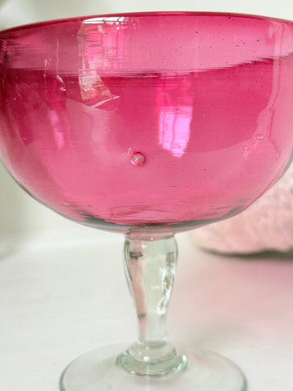Vintage cranberry glass bonbon dish with clear stem and foot, photographed on a white surface