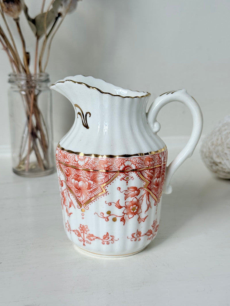 vintage porcelain milk jug with coral transfer design and gilt detailing on white surface