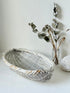Vintage white chippy wicker basket with oval shape and worn painted finish, photographed on white surface.