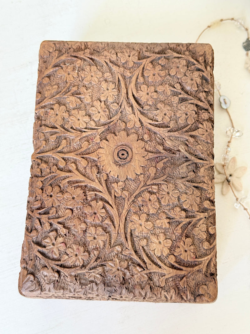 Vintage hand carved wooden jewellery box with floral detail and red fabric lining, photographed on a white surface