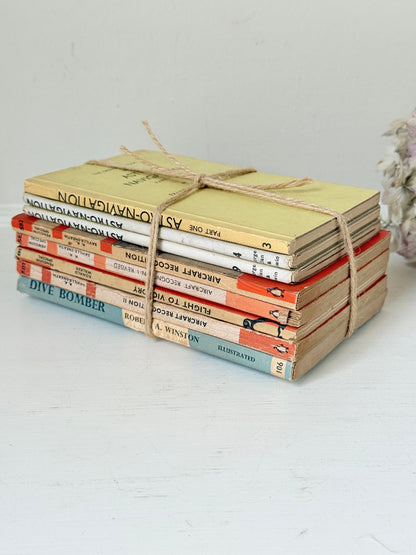 Bundle of vintage Penguin paperback books in orange and cream tones tied with twine, photographed on a white surface