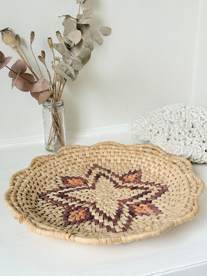 Vintage woven basket tray with star motif photographed on a white surface
