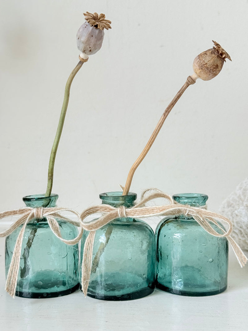 Set of antique green glass ink bottles with rounded forms, photographed on white surface.
