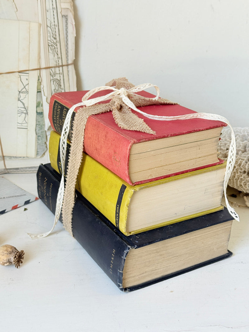 Vintage decorative book bundle in blue yellow and red with aged hardback covers tied with natural ribbon for bookshelf styling
