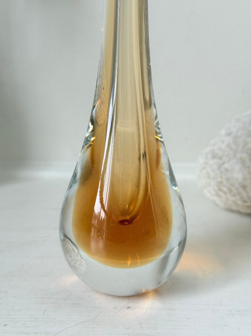 Amber and clear 1960s glass vase with narrow neck and rounded base, photographed on a white surface with dried stems.