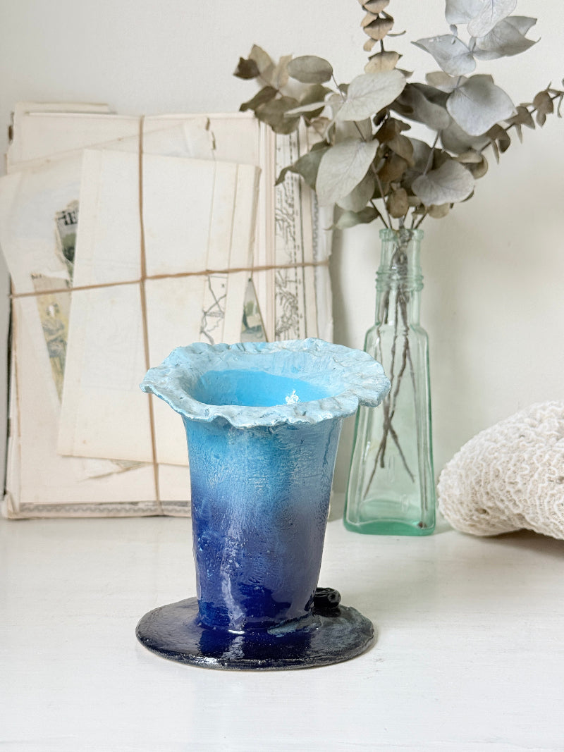 Handmade studio pottery trumpet vase in ombre blue with a frilled rim, photographed on a white surface