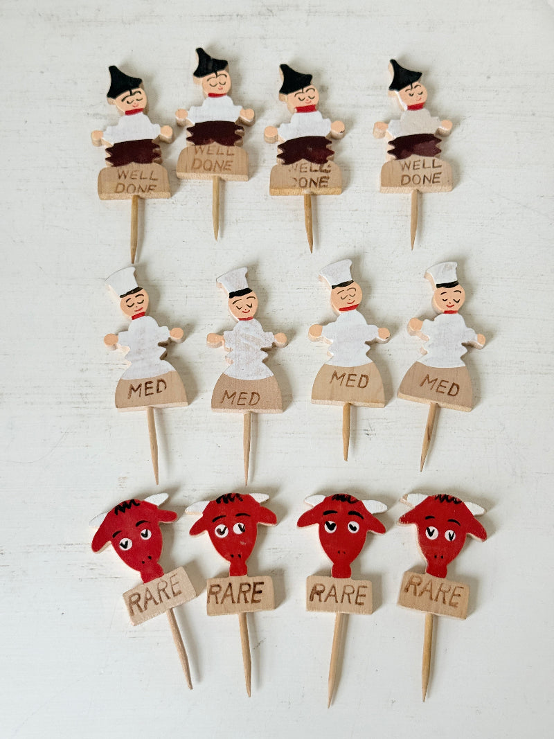 Vintage hand painted wooden steak markers on cocktail sticks labelled rare medium and well done, photographed on a white surface