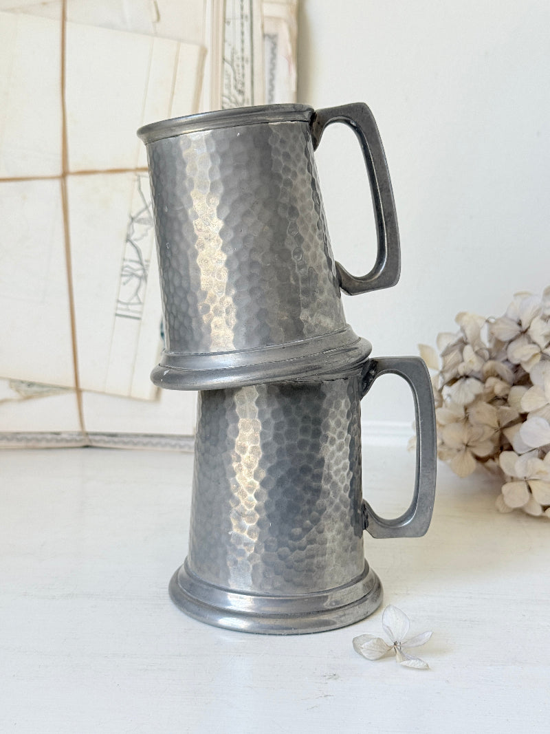 Pair of hammered English pewter tankards by E H Parkin of Sheffield, photographed on a white surface