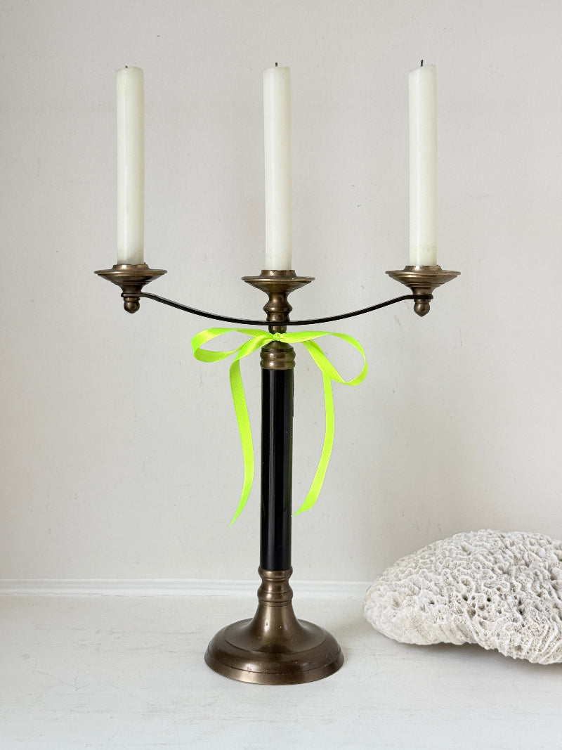 Vintage three arm candelabra in brass and ebonised metal with ivory taper candles styled on a white surface