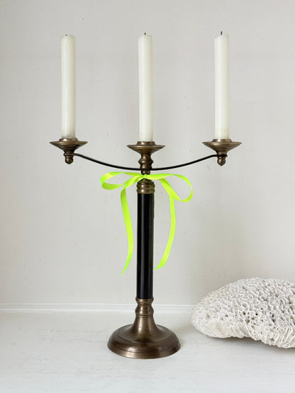 Vintage three arm candelabra in brass and ebonised metal with ivory taper candles styled on a white surface